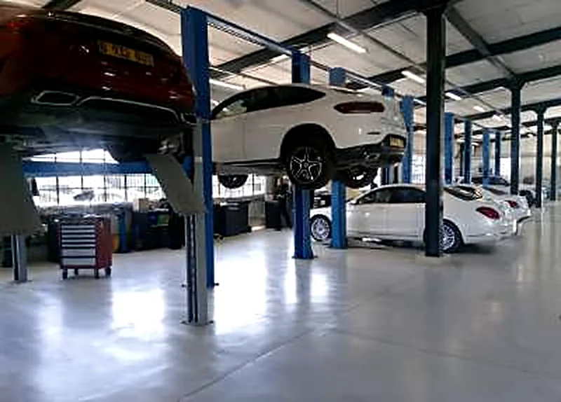 A white SUV raised on a two-post lift